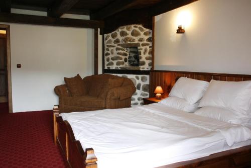 a bedroom with a large bed and a chair at Family hotel Makedonska Kruchma in Dobrinishte
