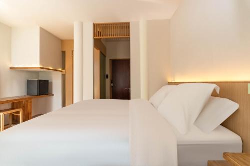 a bedroom with a white bed and a kitchen at cloud and wind in Yangzhou