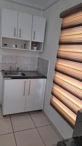 una cucina con mobili bianchi, un lavandino e una finestra di C-Rane Lodge 2 a Phalaborwa