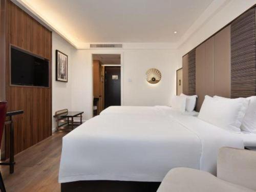 a large white bed in a hotel room at Jinjiang Metropolo Haikou East High Speed Railway Station Normal University in Haikou
