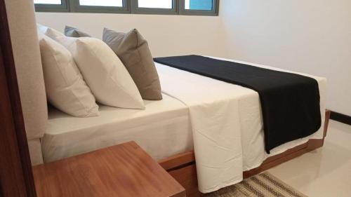 a bed with white pillows and a black blanket on it at Colombo, Trizen Luxury Apartments, Sri Lanka in Colombo