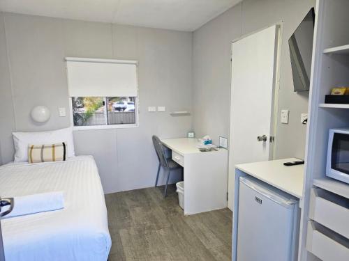 a small hotel room with a bed and a desk at Hive Hotel, Moruya in Moruya