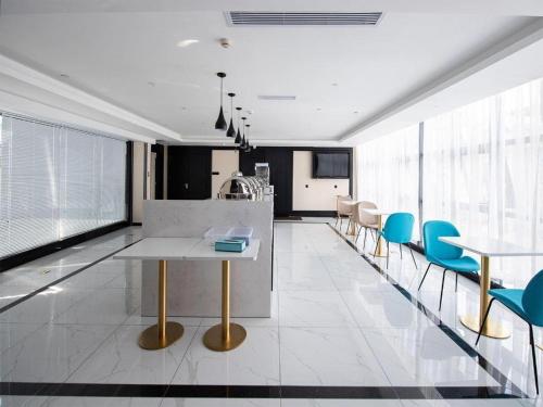 una cucina con sedie blu e tavolo bianco di Xana Hotelle Nanning The Mixc Exhibition Center a Nanning