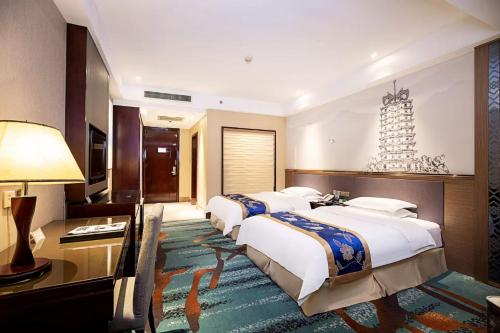 a hotel room with three beds and a desk at Nanbian Fengchegel International Hotel in Zhengzhou