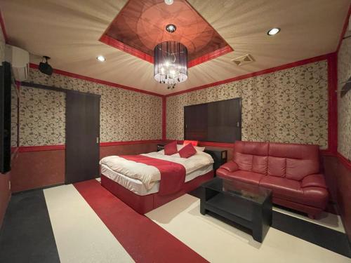 una camera con letto, divano e lampadario a braccio di ホテルアテネ 市原鶴舞インター店 a Ichihara
