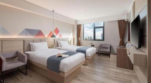 a hotel room with two beds and a television at Borrman Hotel Yuxi Yuxing Road in Yuxi