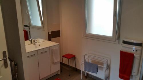 La salle de bains est pourvue d'un lavabo et d'un tabouret rouge. dans l'établissement L'appartement Du Bien être, à Damblain