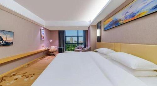 a large white bed in a room with a window at Vienna Hotel Guangdong Zhongshan Xiaolan High-Speed Railway Station in Zhongshan