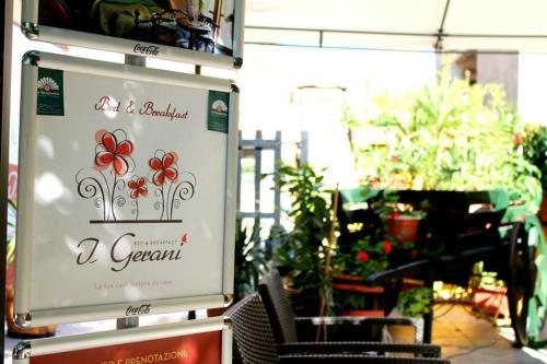 a sign for a garden with red flowers on it at I Gerani in Bosa