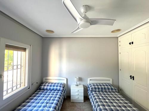 Un dormitorio con dos camas y un ventilador de techo. en Villa de lujo al lado del mar, piscina, garaje wifi, AACC, en Alicante