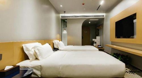 a bedroom with two beds and a flat screen tv at Borrman Hotel Jining High-tech Huangtun in Jining