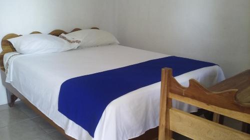 uma cama com lençóis e almofadas azuis e brancos em Cabinas Smith 2 em Cahuita
