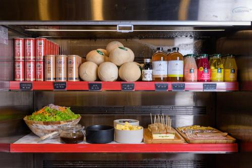 a shelf with food and other food items on it at Wink Hotel Tuy Hoa Beach - 24hrs Stay & Rooftop Pool Bar in Tuy Hoa