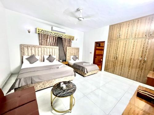 a bedroom with two beds and a table at Amada Family Guest House in Karachi