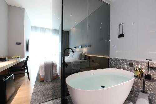 a bathroom with a tub and a bedroom with a bed at Insio Hotel in Shenzhen