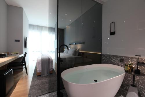 a bathroom with a tub and a bedroom with a bed at Insio Hotel in Shenzhen