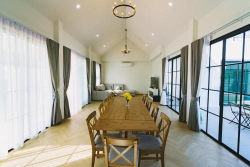 a dining room with a wooden table and chairs at Queenstown Khaoyai in Pak Chong