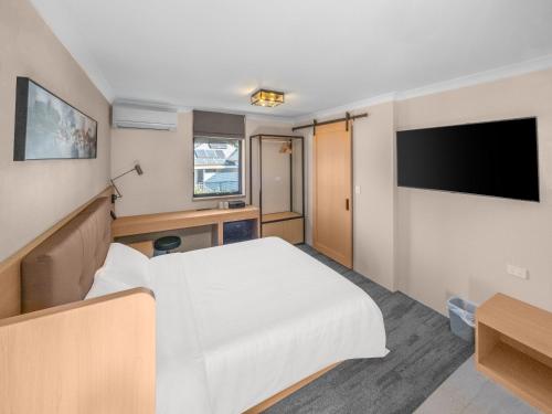 a hotel room with a bed and a flat screen tv at Spring Hill Inn in Brisbane