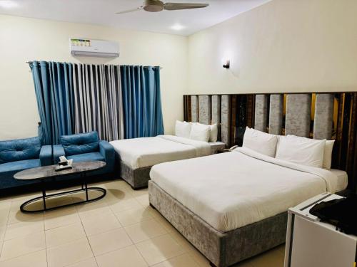 una habitación de hotel con dos camas y un sofá en Solace Inn, en Islamabad