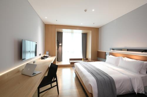 a hotel room with a bed and a desk with a laptop at Insio Hotel in Shenzhen