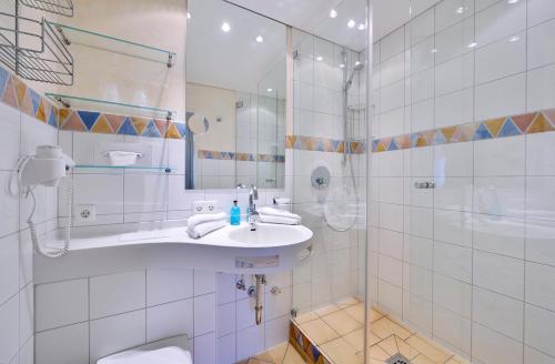 ein weißes Bad mit einem Waschbecken und einer Dusche in der Unterkunft DIE GAMS Hotel Restaurant in Bad Hindelang