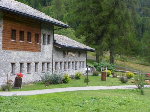 a stone building with a grass yard next to a house at Hotel Les Granges in La Thuile