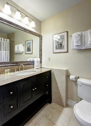 a bathroom with a sink and a toilet and a mirror at Hotel St. Pierre French Quarter in New Orleans