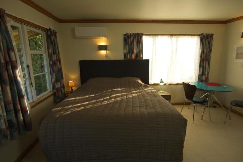 a bedroom with a bed and a table and windows at Hilltop guest room, Escape the city! in Pukehiki