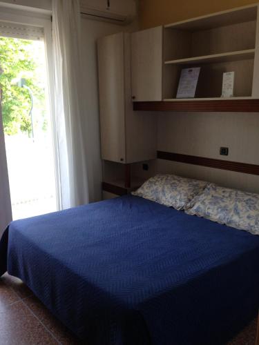 a bedroom with a blue bed and a window at Pensione Imperia in Lignano Sabbiadoro