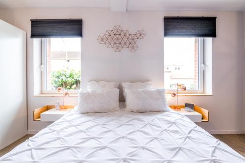 a bedroom with a large white bed with two windows at B&B La Maison de Julia in Albi