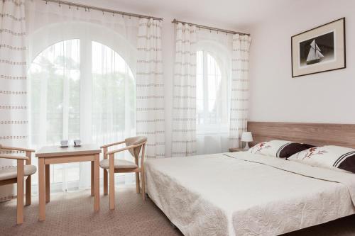 a bedroom with a bed and a table and a chair at Willa Portowa - 120 metrów od plaży in Dziwnów