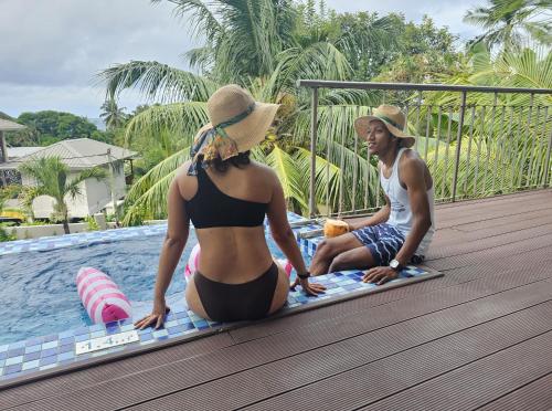 a man and a woman sitting on a mat by a pool at Moulin Kann Villas in Mahe