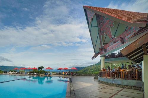 a resort with a pool and people sitting at a bar at Hotel Niagara Parapat in Parapat