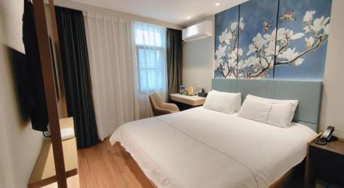 a bedroom with a white bed and a painting on the wall at Magnotel Shanghai Henglong Plaza in Shanghai
