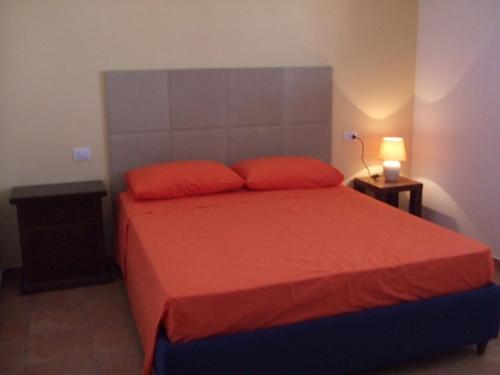 sypialnia z czerwonym łóżkiem i 2 czerwonymi poduszkami w obiekcie Residence La Corte w mieście Porto Cesareo