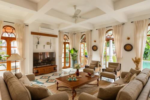 AssagaoにあるVilla Giulietta - 4BHK Villa in Assagao with Big Pvt Pool, Balcony, Dedicated Caretaker, Near Famous Cafesのソファとテーブルのあるリビングルーム
