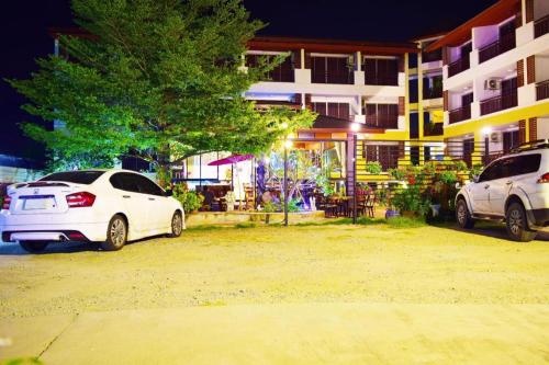 two white cars parked in front of a building at Nantharom Hotel and Restaurant in Chachoengsao
