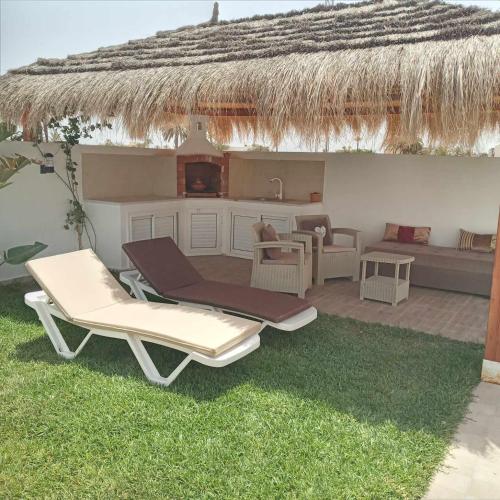 a patio with two lounge chairs and a kitchen at Villa sweet Djerba A 5km de la plage et de centre Midoun in Arkou