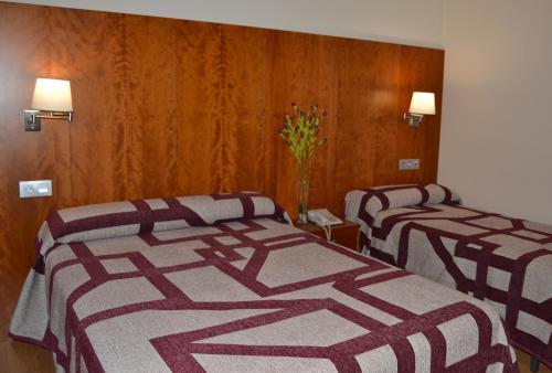 two beds in a hotel room with striped blankets at Hotel Jarama in Zamora