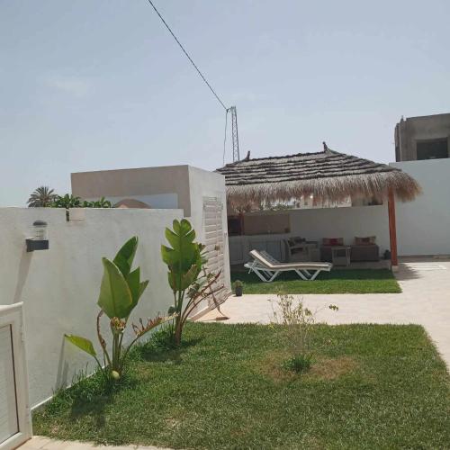 a house with a patio with a couch and a straw roof at Villa sweet Djerba A 5km de la plage et de centre Midoun in Arkou