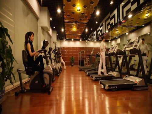 a woman sitting on a exercise bike in a gym at Capital Hotel in Beijing