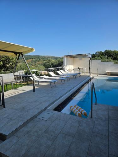 a swimming pool with chaise lounge chairs on a patio at Villa Paola Pantalica in Cassaro