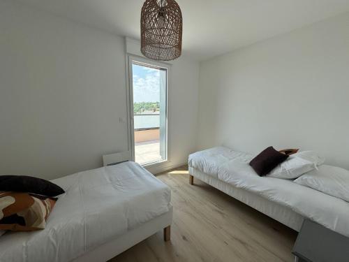 Cette chambre blanche dispose de deux lits et d'une fenêtre. dans l'établissement Appartement Le Riva B304, à Barneville-Carteret