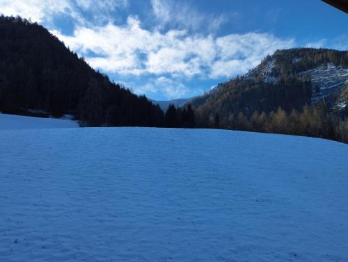 a snow covered field with mountains in the background at Planerhof Apartment Lilie in Funes