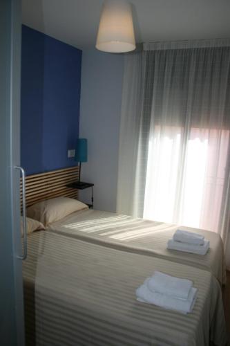 a bedroom with two beds and a window with towels at Hostal La Lluna in Arenys de Mar