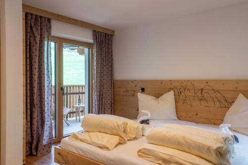 a bedroom with a bed with a wooden headboard at Planerhof Apartment Alpenrose in Funes