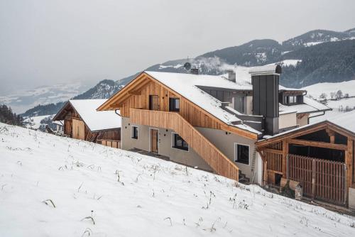 a building on a snow covered hill with snow at Planerhof Apartment Alpenrose in Funes
