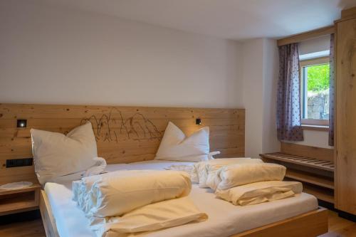 a bedroom with a bed with white sheets and pillows at Planerhof Apartment Alpenrose in Funes