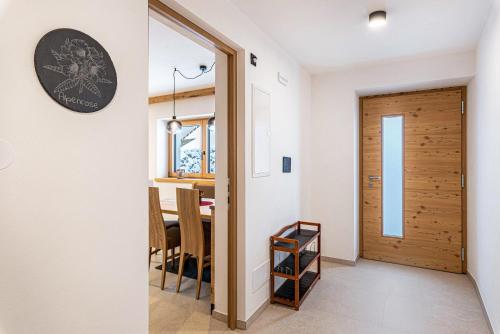 a kitchen and dining room with a table and a door at Planerhof Apartment Alpenrose in Funes