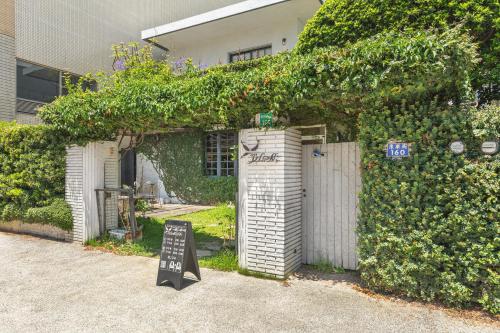 a building covered in ivy with a sign in front of it at IsShoNi house in Tainan